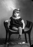 Porträtt på en flicka, sittande på en pall.