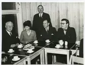 Människor i kostym och klänning som dricker kaffe.