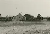 En gård i Klockholm. Några bodar och bostadshus i träfasad.