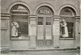 Nordiska museets entré i södra paviljongen, Drottninggatan 71 A 1898 med dräktdockor i fönstren. Ur Ny Illustrerad Tidning 1898. 