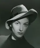 Porträtt av modell i grå filthatt med brunt skärp.