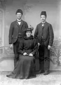 Gruppbild av två herrar och sittande kvinna.