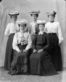 Groppfotografi av fem damer i stora hattar.