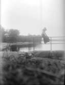 Exteriör.Otydlig. (Strandvy med kvinna.) Fotograf: Ellen Kock? Axel Lundbäck m.fl.Gullspångssamlingen.Bilder från Gullspång med omnejd.