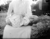 Exteriör. Dam med barn i knäet, misslyckat foto. Fotograf: Ellen Kock? Axel Lundbäck m.fl. Gullspångssamlingen.Bilder från Gullspång med omnejd.