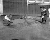 Marie-Louise Berg och Knut Zetterman leker i sandhög utanför Knutstorps köksfönster.

Marie-Louise Berg, gift Grauers, f. 1914.

Kapten Sigge Flachs samling, Prinshaga, Axvall.