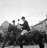 Olympiska elden anländer till Skara 1956. Skararyttaren Bertil Holmqvist mottager elden på Stora Torget.