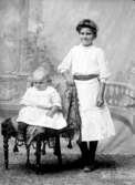 Ateljé. Ung dam och barn i stol.Fotograf: Ellen Kock? Axel Lundbäck m.fl.Gullspångssamlingen.Bilder från Gullspång med omnejd.