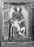 I Västergötlands museums samlingar. 
Inv.nr. 7798.

PietÃ , framställning av den sörjande jungfru Maria, sittande med den döde Kristus i sitt knä. Motivet har sin bakgrund i senmedeltidens passionsmystik och uppstod i Rhenområdet i början av1300-talet. Det blev därefter vanligt i både måleri och skulptur. En ensam sörjande Maria kallas mater dolorosa. 
http://www.ne.se/jsp/search/article.jsp?i_art_id=283310