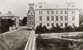 Järnvägsgatan vid mitten av 1880-talet.
På bilden synes det av Skaraborgs läns allmänna sparbank 1874 uppförda bankhuset, som sedermera försålts och påbyggts med en våning.
Det nuvarande stora bankhuset invid det förra uppfördes 1904.