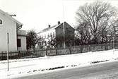 Till vänster hörnhuset Bragegatan 8/Sandåsgatan 10. En väg, staket och bostäder i vinterlandskap.