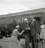 Gustaf V, stödd på borgmästare Yngve Malmqvist, hälsar på landshövdingefrun Wagnsson framför en tågvagn.