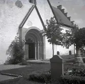 En kyrka, portal och gravstenar.