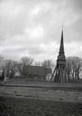 En klockstapel, kyrkogård och kyrka. Pelarne kyrka.