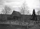 En klockstapel, kyrkogård och kyrka. Djursdala kyrka.