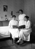 Tre unga kvinnor tittar i fotoalbum

