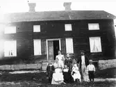 Familjegrupp framför hus.
