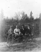 Tre män och en kvinna på en bänk.
