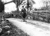 Man med cykel poserar framför gärdsgård.