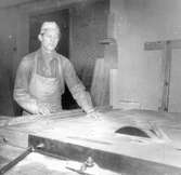 Vid Habo Laggkärlsfabrik på Munkvägen 8, arbetar Evald Skoglund vid en cirkelsåg med tillsågning av plywood till tunnor.