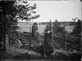 En kvinna sitter på gärdesgården och en kvinna sitter på en sten, Östhammar, Uppland