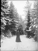 Kvinna står på en snöig väg, Östhammar, Uppland