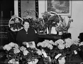 Kvinna omgiven av blommor, Östhammar, Uppland 1952