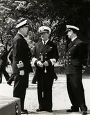 Tre män i samspråk.