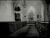 Interiörbild av Follingbo kyrka på Gotland. Altare, predikstol, snidad bänkinredning, kor.