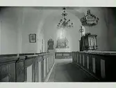 Interiör från okänd kyrka. Altargång, altare, predikstol, kyrkbänkar.