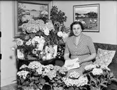 Kvinna i bostadsmiljö omgiven av blommor, Östhammar, Uppland