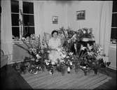 Kvinna i bostadsmiljö omgiven av blommor, Östhammar, Uppland