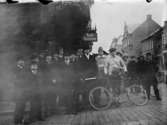 Utetagning vy 1920. Repro Algatan, en mängd herrar, en man med sin cykel.