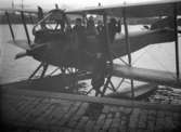 Utetagning vy 1920. Dubbeldäckflygplan med 6 personer i hamnen.