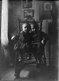 Alf och Roland Liljefors gungar i gungstol i hemmet, möjligen i Göteborg 1906-1907