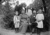 Pontus och Hildegard Liljefors med barnen Matts, Margareta, Måns, Kristina, Per samt Elisabeth, sitter ute i trädgård, i Sverige