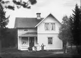 Karl Erikssons gård Ö. Ärnäs. Karl R. stödjer björken. Lispa Edvard Persson sitter på trappan med okänd. Johanna Eriksson, döttrarna Elin o Karin samt Selma Forsman