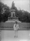 Liten pojke i sjömanskostym framför Linnéstatyn i Humlegården, Stockholm efter 1885