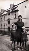 Fabriksarbeterskan Sonja Johansson (1908 - 1977) står med döttrarna Ninnie (f 1937) och Britt-Marie (1939 - 2004) framför sig, år 1943. I bakgrunden ses Gustavsberg 3. Sonja sydde alltid flickornas klänningar, och dessa som är med på bild var röda med vita prickar på. 
Ninnie berättar 