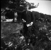 En orienterare på ett fält vid skogsbrynet.