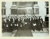 Snett bakom blombuketten i mitten står en sångare, som är ensam om att ha svart fluga: hans namn är Gustaf Hjalmar Johansson (anfader till släkten Klette i Kalmar), född 17/5 1863, död  1935. Bodde på Tullslätten och var landsfiskal (son till storsångaren och kantorn i Åby: Johan Alfred Johansson.)