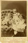 Porträtt av tre små flickor i en fotoateljé.