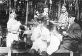 Utanför Bredaryd är kaffebordet dukat. Till höger sitter sadelmakare Emil Lundin och bakom honom står hans fru Gerda, deras barn vid grammofonen är Paul, Gertrude och Elsa.