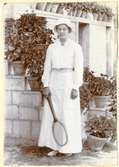 Porträtt av Marie-Louise Flygare (g. Lundberg) i Persien 1913–14. Hon är klädd i ljus klännning och solhatt och håller i ett tennisrack.