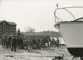Sjösättning av båt, i bakgrunden till vänster Elkvarnen, byggd 1882, verksam som elkvarn fr o m 1905.
Personer: Torsten Svenson, går tvåa från vänster