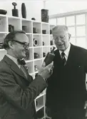 Kungligt besök på Gustavsbergs porslinsfabrik. Stig Lindberg förevisar en av sina stengodsvaser.
Personer: Kung Gustav VI Adolf och Stig Lindberg