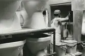 Interiör, Sanitetsporslinsfabriken. Sprutglasering i sprutskåp av wc-stolar.
Personer: okänd