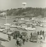 Exteriörbild. Gustavsbergs centrum. Domus-parkeringen med Svenska Handelsbanken och grillkiosk. Vattentornet i bakgrunden och nedanför Rutens lada som brann ned på 1990-talet.
Personer: Okända personer.