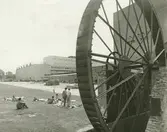 Exteriör. Vattenhjulet och rastande fabriksarbetare.
Personer: okända