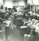 Interiör. Företagsgymnastik på arbetstid. Ledare i mitten: Svea Box.
Personer: Svea Box och okända